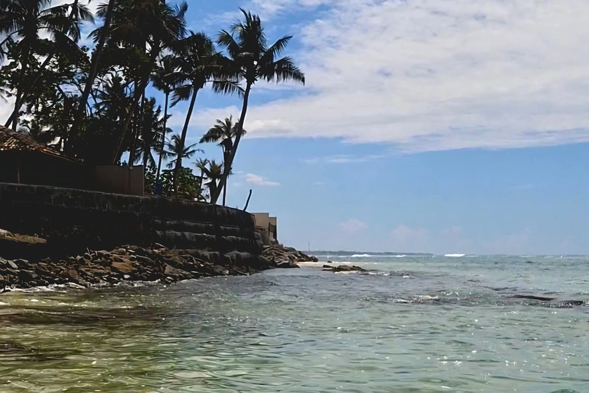 Tipico scorcio di una spiaggia del sud dello Sri Lanka con acque cristalline, spiagge di sabbia chiara e palme.